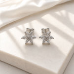 Pair of silver star-shaped earrings on a light beige fabric background