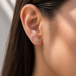 Close-up of an ear wearing a star-shaped earring with a neutral background